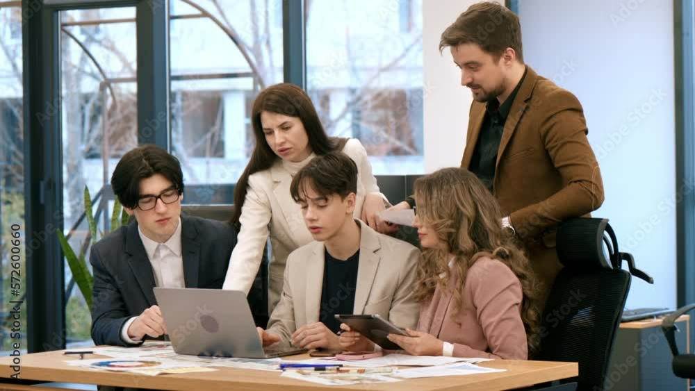 Business meeting in an office, workers discussing business affairs using laptop. Papers with charts on the table Business meeting in an office, workers discussing business affairs using laptop. Papers with charts on the table