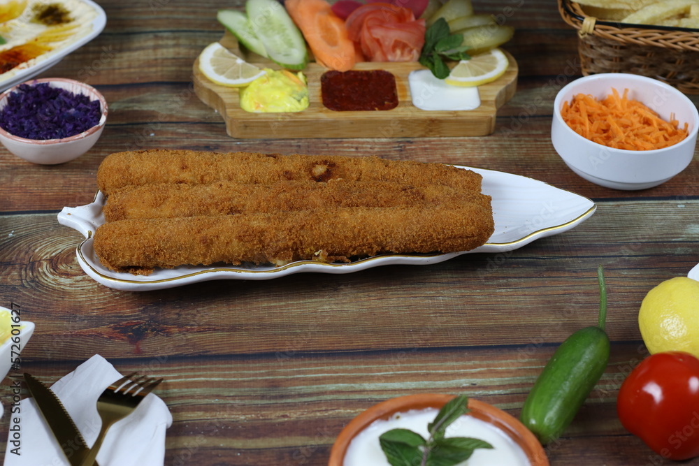 Crispy Fried Chicken Fingers Served Elegantly on Wooden Dining Table with Vegetables and Sauces Crispy Fried Chicken Fingers Served Elegantly on Wooden Dining Table with Vegetables and Sauces
