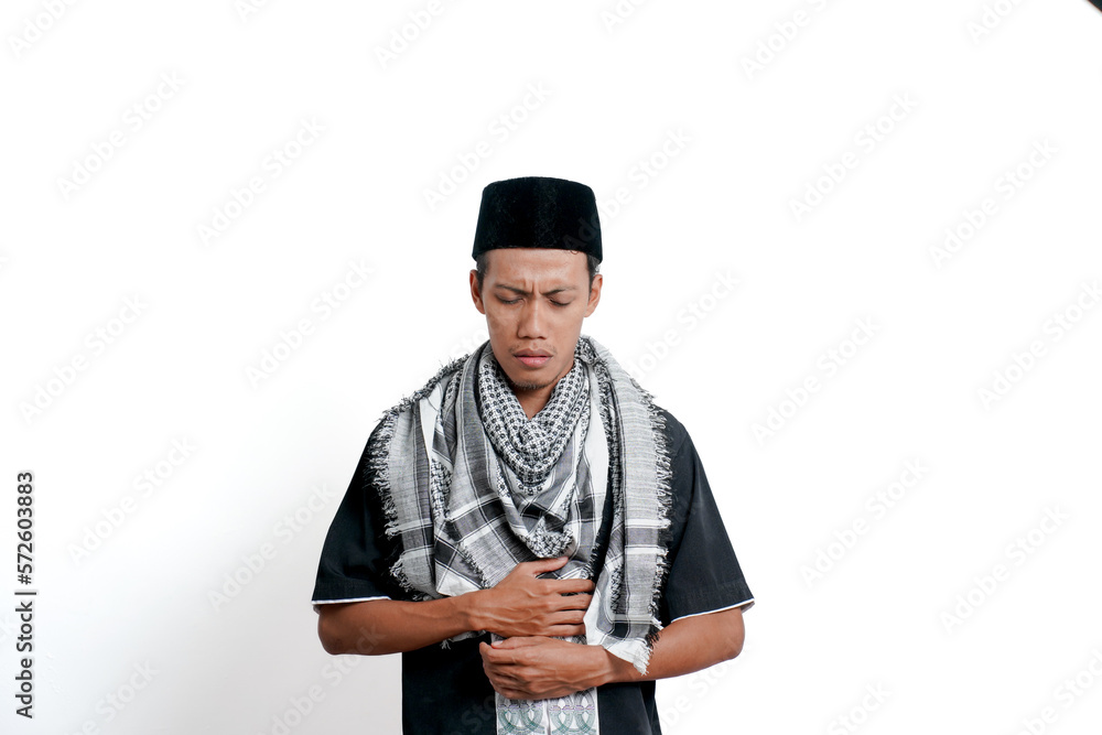 Religious muslim asian man wearing turban, muslim dress and cap, feeling pain due to stomach ache or ulcer. Isolated on white background. Religious muslim asian man wearing turban, muslim dress and cap, feeling pain due to stomach ache or ulcer. Isolated on white background.