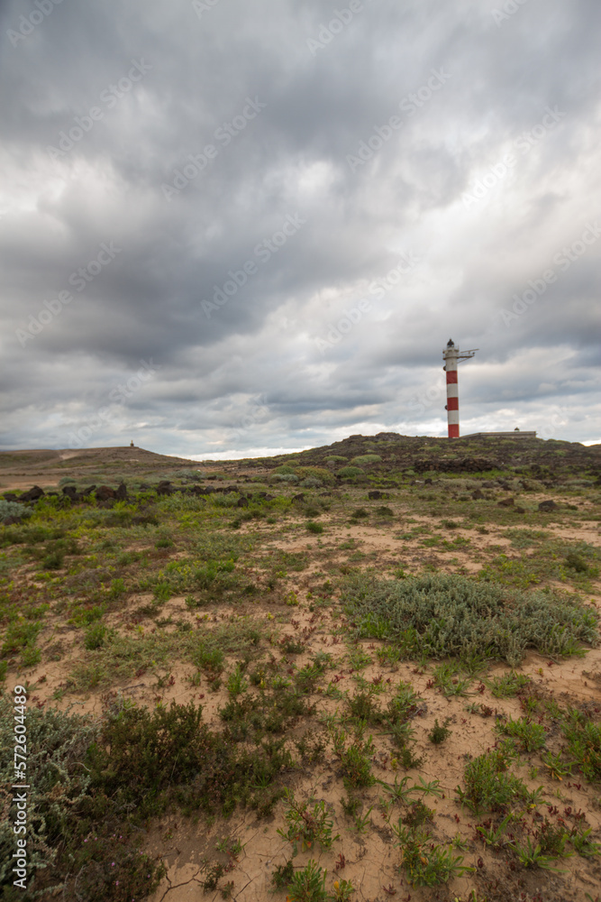 Desert landscape with volcanic rocks, lighthouse and storm clouds. Aabdes, Tenerife, Canary Islands. Spain
