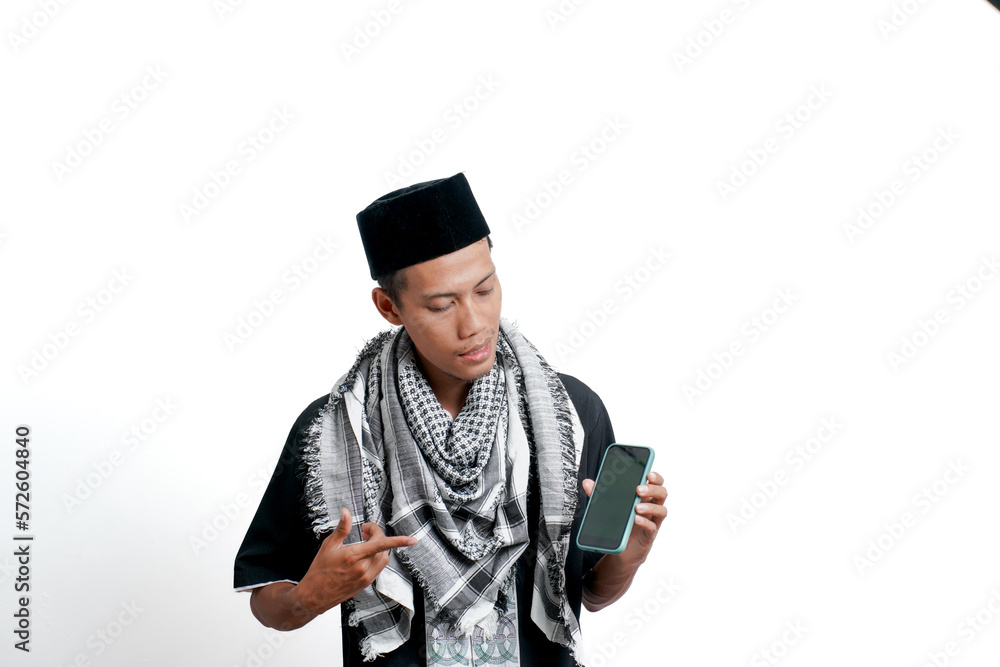 Religious muslim asian man wearing turban, muslim dress and cap. Pointing at the smartphone screen, feeling happy, surprised or calm. isolated on white background. Religious muslim asian man wearing turban, muslim dress and cap. Pointing at the smartphone screen, feeling happy, surprised or calm. isolated on white background.