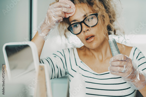 One woman doing dye hairstyle colouring alone at home with beauty health care hair tools and process. Aging control for young adult female people. Lady with glasses using chemical or natural products
