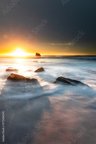 Sunset while sea waves hitting the rocks on the beach; at Ilbarritz beach in Biarritz, Basque Country.