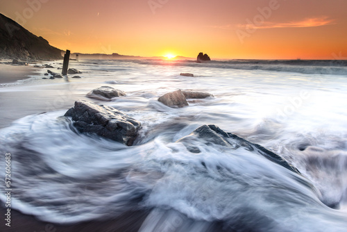 Sunset while sea waves hitting the rocks on the beach; at Ilbarritz beach in Biarritz, Basque Country.