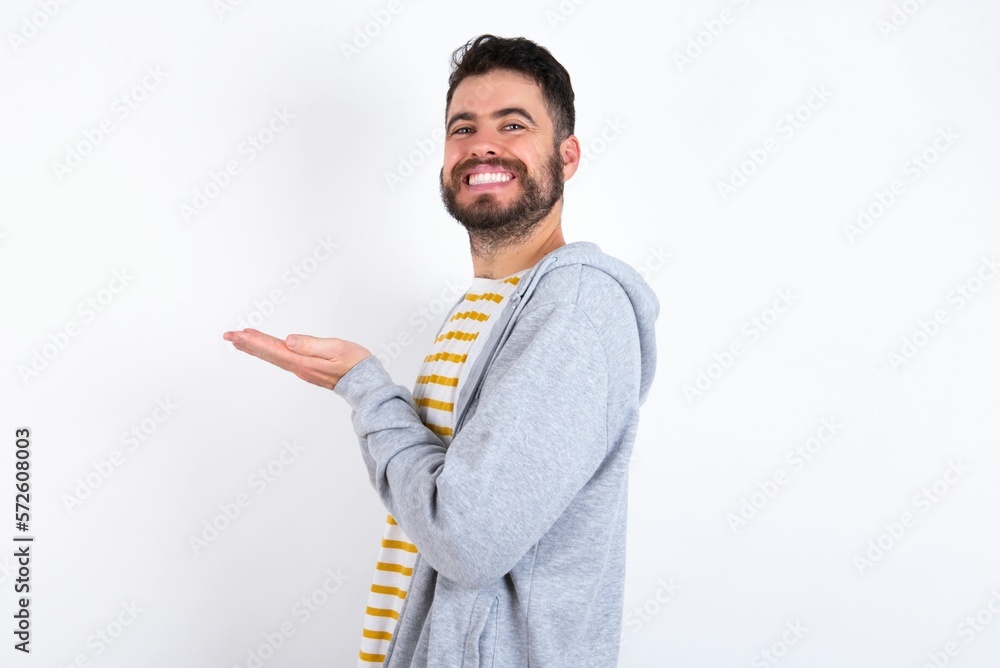 caucasian man wearing casual sportswear over white wall pointing aside with hands open palms showing copy space, presenting advertisement smiling excited happy caucasian man wearing casual sportswear over white wall pointing aside with hands open palms showing copy space, presenting advertisement smiling excited happy