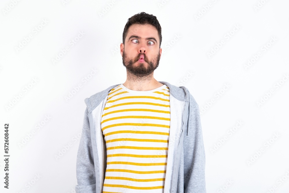 caucasian man wearing casual sportswear over white wall making fish face with lips, crazy and comical gesture. Funny expression. caucasian man wearing casual sportswear over white wall making fish face with lips, crazy and comical gesture. Funny expression.
