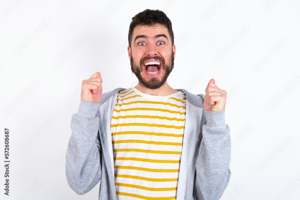 caucasian man wearing casual sportswear over white wall celebrating surprised and amazed for success with arms raised and open eyes. Winner concept. caucasian man wearing casual sportswear over white wall celebrating surprised and amazed for success with arms raised and open eyes. Winner concept.
