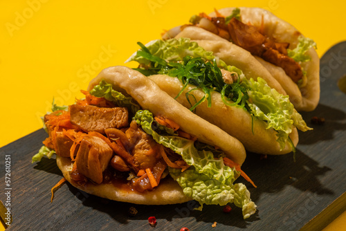 Bao buns three pieces on a wooden board, yellow background, hard light. photo