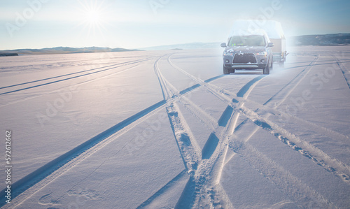 A moving car (SUV) on lake Baikal - Car tire tracks (trail) in fresh snow - Baikal Lake, Siberia 