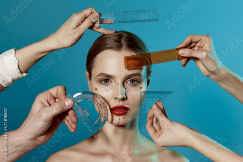 Making beauty, modifying face to make non-surgical or surgical correction, plastic surgery. correction of asymmetry. Young woman, female patient isolated on blue studio background. Lifting concept