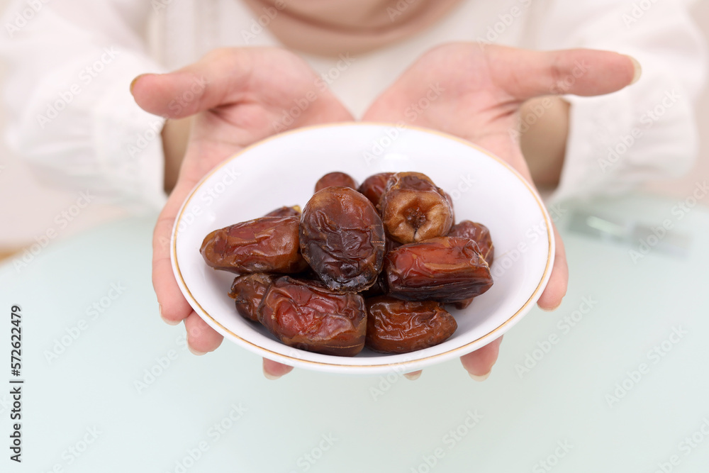 Young asian muslim woman's hand holding a plate of date palm fruit. Ramadhan concept. Young asian muslim woman's hand holding a plate of date palm fruit. Ramadhan concept.