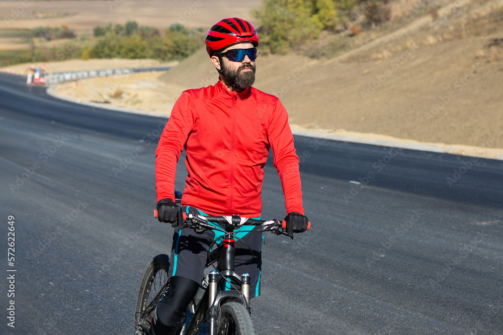 Cyclist riding bicycle on road against clear sky. A man in an outfit stands with a bicycle on an autumn sunny day. Cyclist riding bicycle on road against clear sky. A man in an outfit stands with a bicycle on an autumn sunny day.