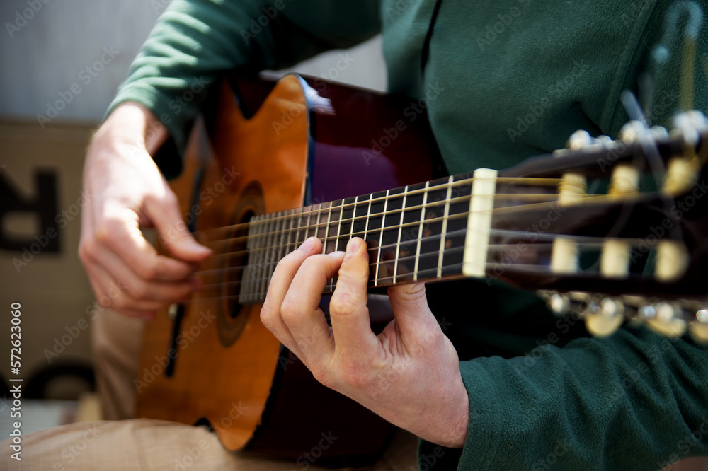 Plays the guitar. Guitar strings and fingers. Musical instrument. Man and guitar