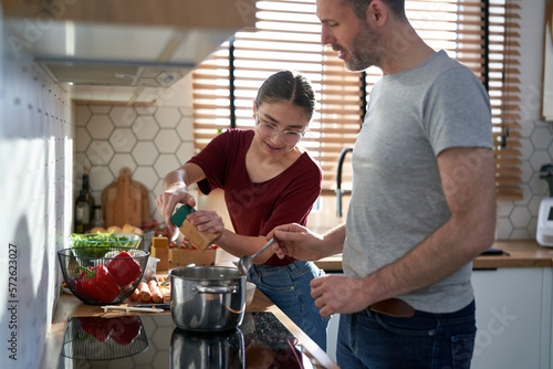 Obraz na plátně Caucasian man cooking with teenager daughter at home
