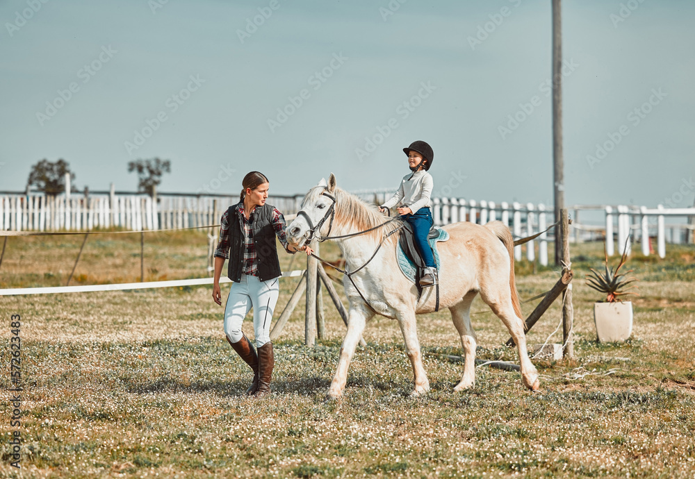 .Lesson, help and woman with a child on a horse for learning, sports and hobby on a farm in Italy. Helping, support and coach teaching a girl horseback riding for a physical activity in countryside.