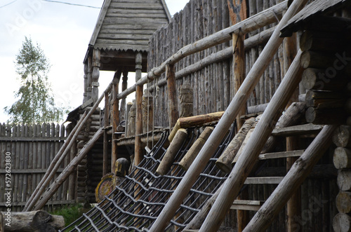 Wooden fortress wall against the sky. Medieval fortress with high walls. Wooden installation in the style of an ancient city. Stockade fence made of logs. Summer tourism and travel