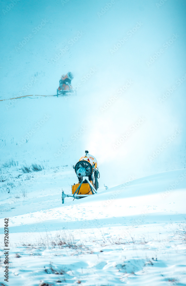 Snow cannon in winter mountains. Snow-gun spraying artificial ice crystals. Machine making snow. Strbske pleso (Strbske lake) ski resort with snow.