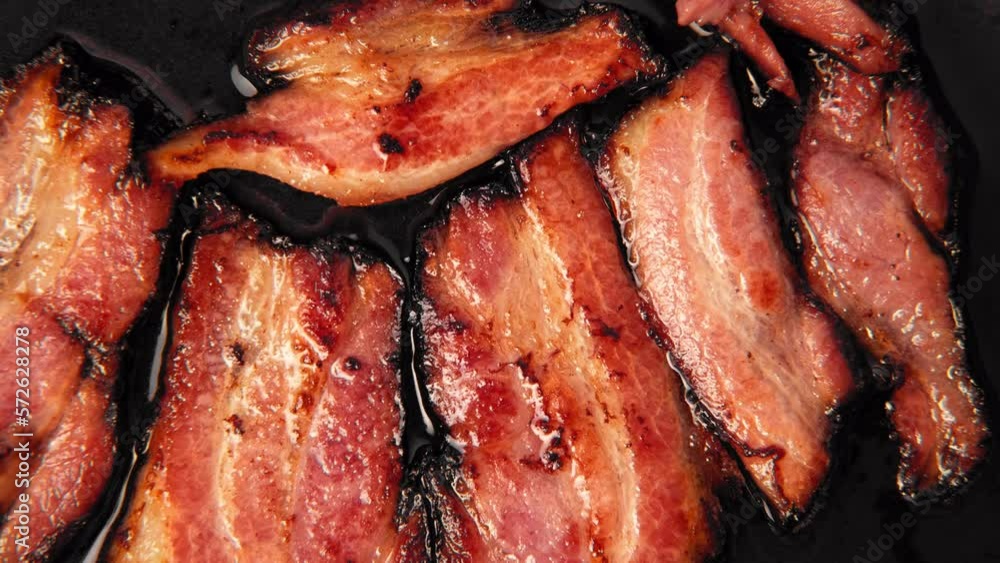 Frying Bacon Slices in a Pan. Crispy Pieces of Delicious Red Thin Smokey Bacon Fried in a Hot