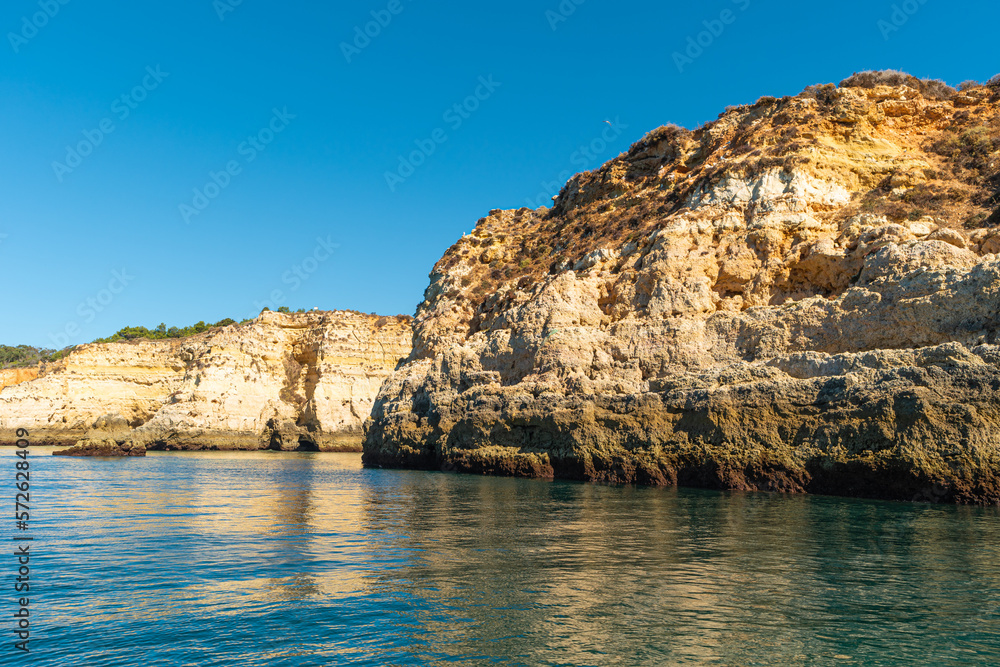 Natural caves and beach, Algarve Portugal. Rock cliff arches and turquoise sea water on coast of Portugal in Algarve region. View from the sea