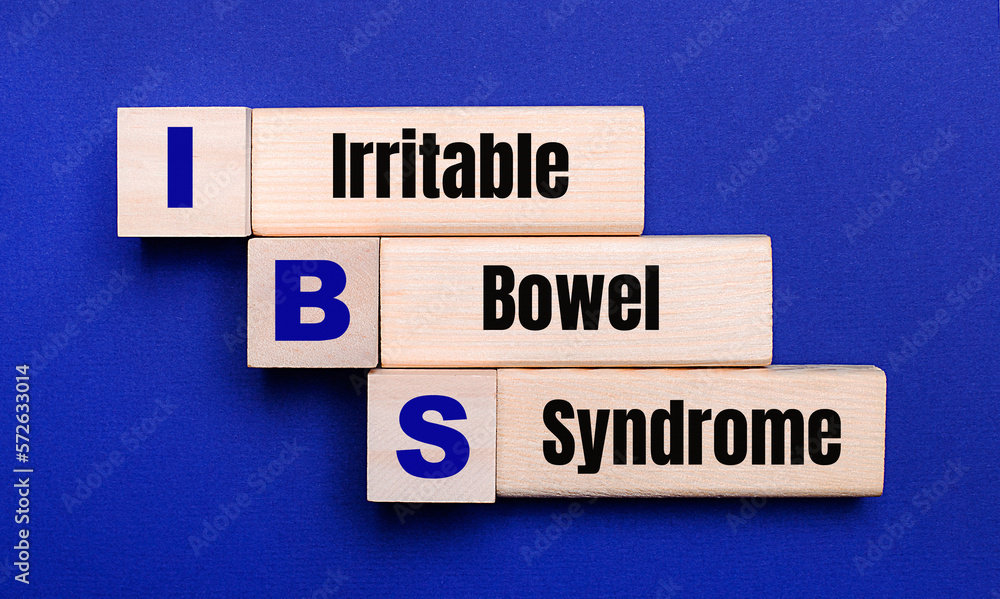 On a bright blue background, light wooden blocks and cubes with the text IBS Irritable Bowel Syndrome