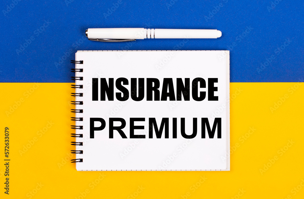 Obraz premium A white notebook with the text INSURANCE PREMIUM and a white pen on a blue and yellow background.
