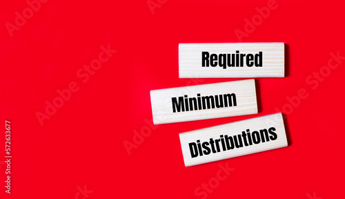 Three wooden blocks with the text RMD Required Minimum Distributions on a bright red background. Copy space
