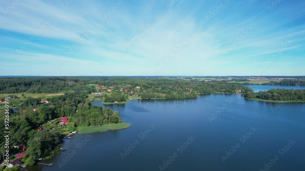 Majestic Aerial View of Calm Lake With Islands in Poland. Impressive Lake Houses. Village Houses on Shore of Paradise Lake. Peaceful Reflected on Water. Cottages Between Green Trees, Forest and Hills. Majestic Aerial View of Calm Lake With Islands in Poland. Impressive Lake Houses. Village Houses on Shore of Paradise Lake. Peaceful Reflected on Water. Cottages Between Green Trees, Forest and Hills.
