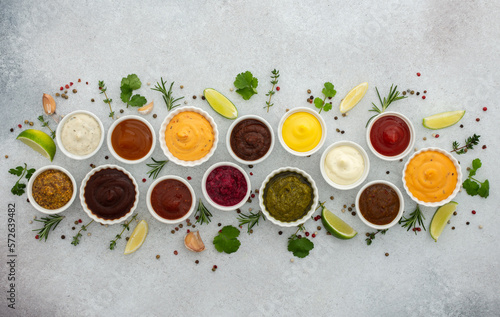 Different types of sauces in bowls with seasonings  rosemary and pepper  thyme and garlic  lime and lemon  cilantro  top view  copy space
