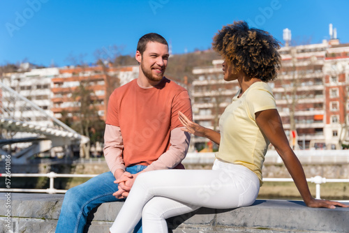 Multiracial couple on city street, lifestyle, sitting smiling talking on vacation