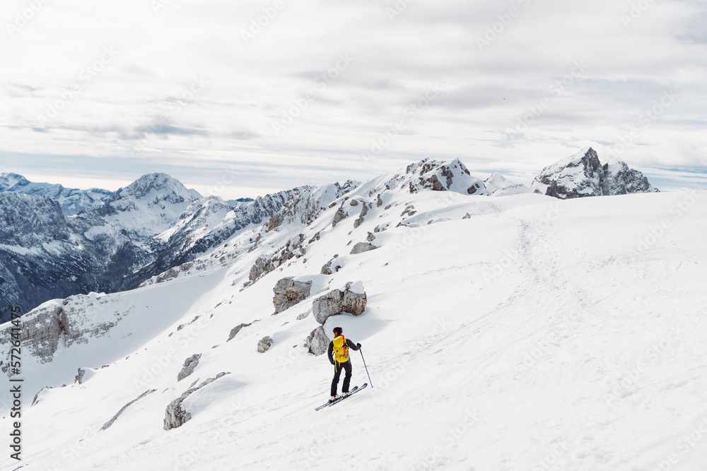 One lonely ski tourer skiing down the snowy mountain 