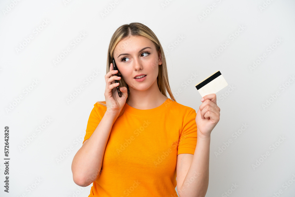 Young caucasian woman isolated on white background keeping a conversation with the mobile phone and holding a credit card Young caucasian woman isolated on white background keeping a conversation with the mobile phone and holding a credit card