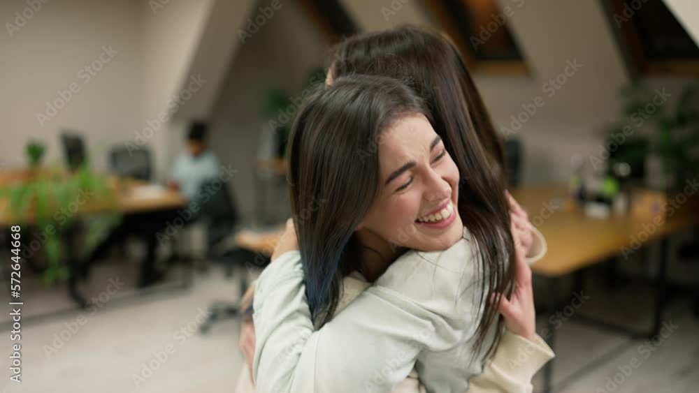Young female office workers hugging to congratulate a colleague or missing a friend from vacation Young female office workers hugging to congratulate a colleague or missing a friend from vacation
