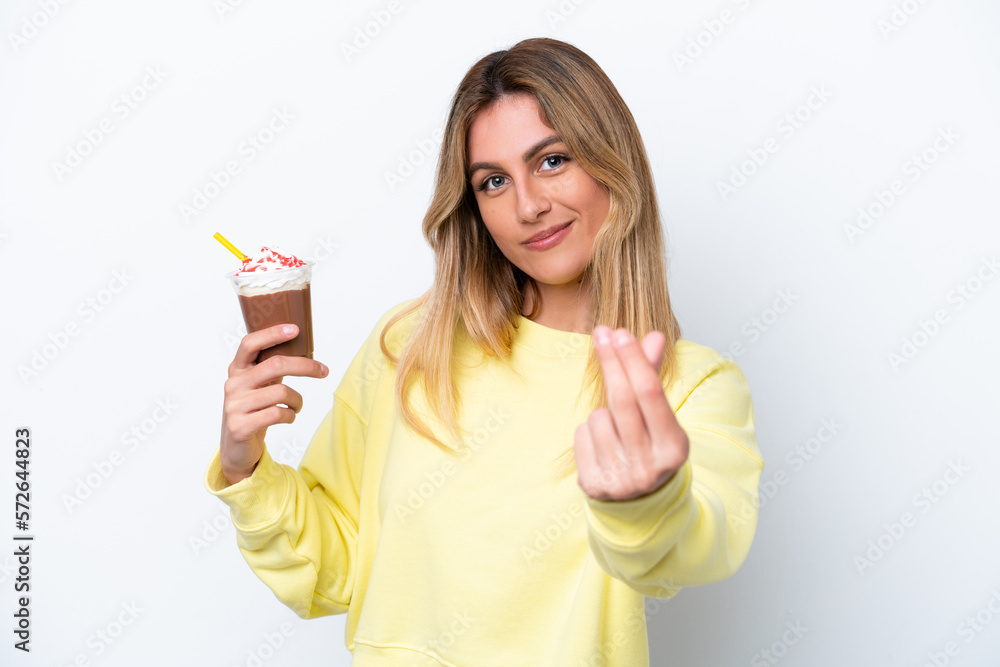 Young Uruguayan woman holding Frappuccino isolated on white background making money gesture Young Uruguayan woman holding Frappuccino isolated on white background making money gesture