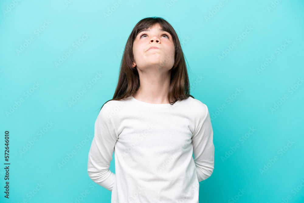 Little caucasian girl isolated on blue background and looking up Little caucasian girl isolated on blue background and looking up