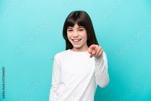 Little caucasian girl isolated on blue background surprised and pointing front
