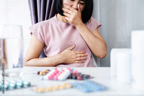unwell Asian woman feeling nausea and want to vomit side effect of taking too much antibiotics pill can be used for Ulcerative Colitis concept
