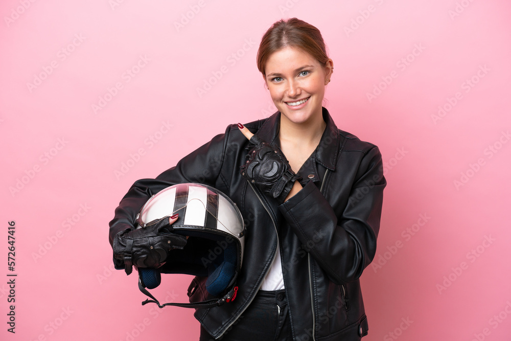 Young caucasian woman with a motorcycle helmet isolated on pink background pointing to the side to present a product Young caucasian woman with a motorcycle helmet isolated on pink background pointing to the side to present a product
