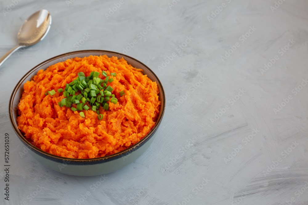 Homemade Creamy Mashed Sweet Potatoes with MIlk and Butter in a Bowl on a gray background, side view. Space for text.