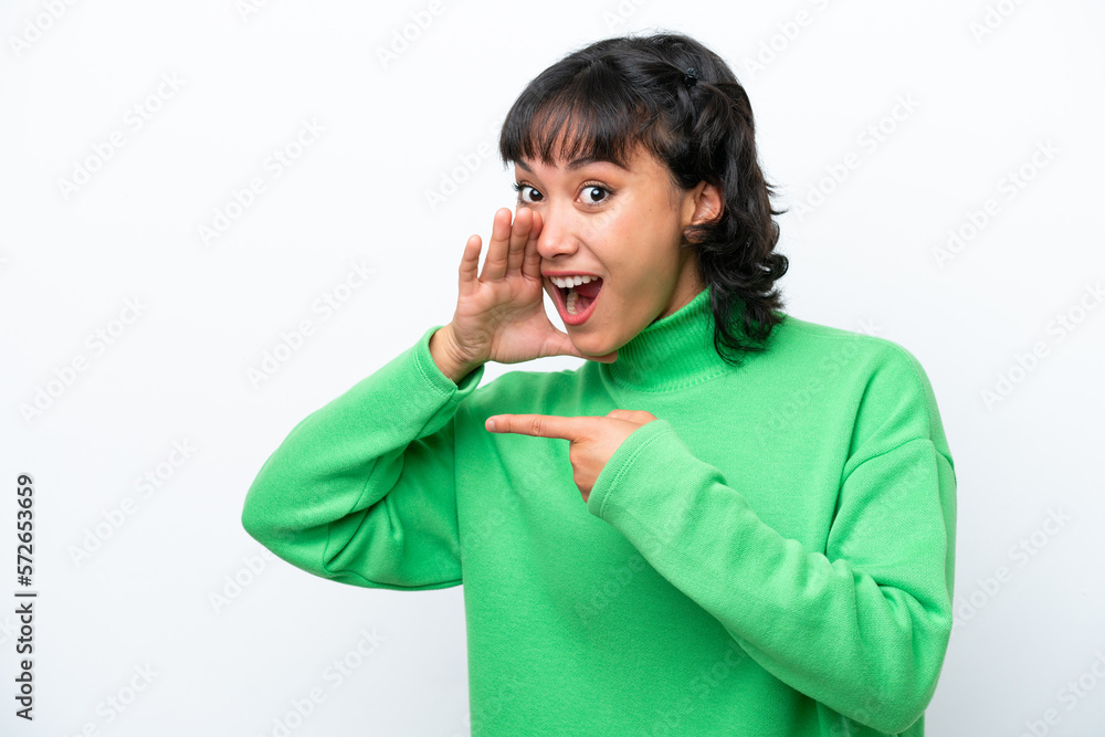 Young Argentinian woman isolated on white background pointing to the side to present a product and whispering something Young Argentinian woman isolated on white background pointing to the side to present a product and whispering something