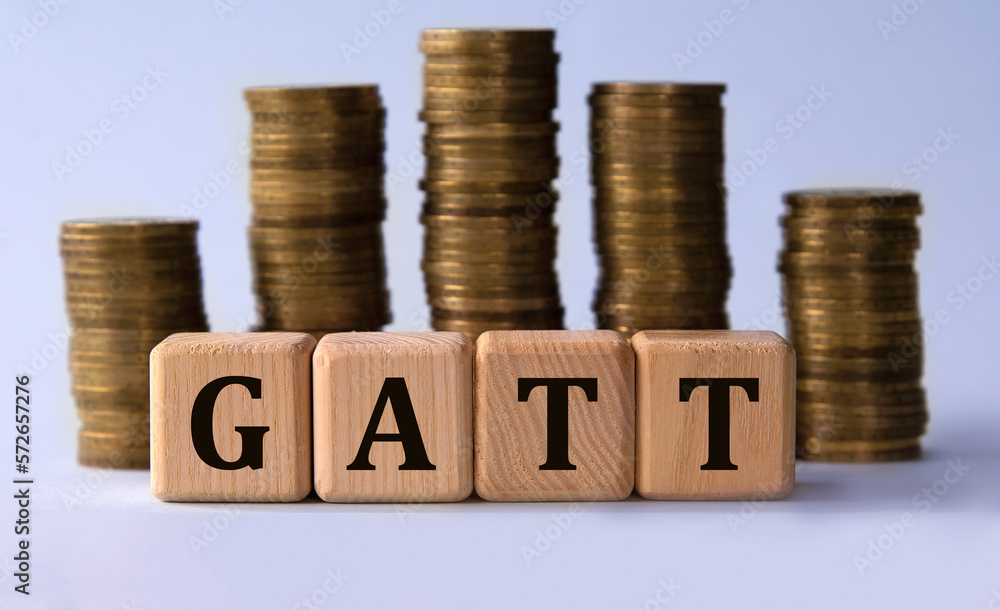 GATT - acronym on wooden cubes on the background of stacks of coins GATT - acronym on wooden cubes on the background of stacks of coins