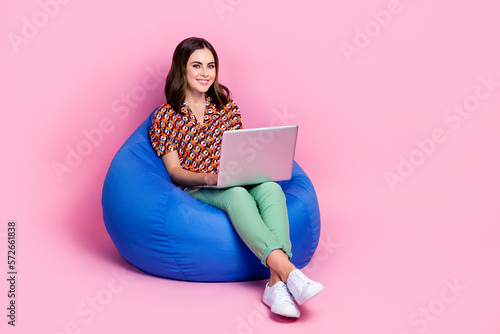 Full body length size photo of youngster attractive business lady sitting bean bag online working remote laptop isolated on pink color background