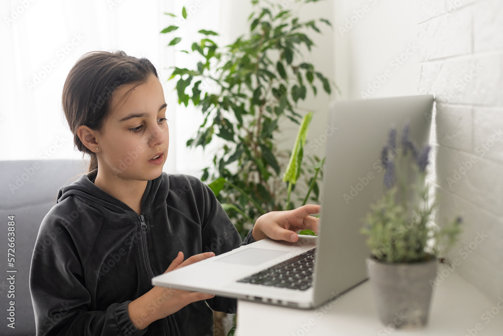 Distant education. Friendly teen girl having online lesson via laptop and showing gesturing in sign language, studying online from home