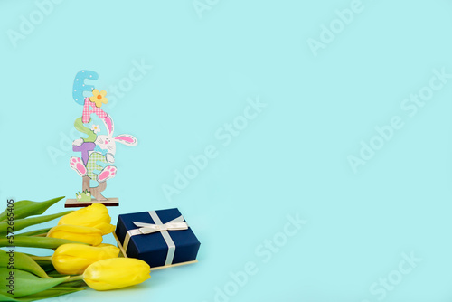 Gift box with a bouquet of yellow tulips and the inscription groin on a blue background with space for text. Postcard, congratulations. High quality photo