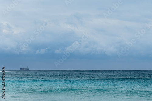 A lone cargo ship journeys into the distance of the open ocean
