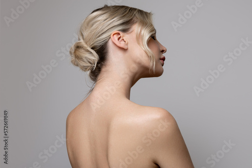 Fotografie Young beautiful woman stands on her side with bare shoulders and back