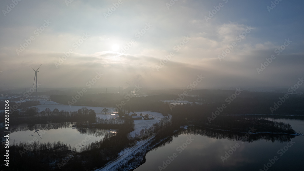 Aerial landscape of the frozen lake and forest in the snow in Belgium at sunset shot by a drone. High quality photo