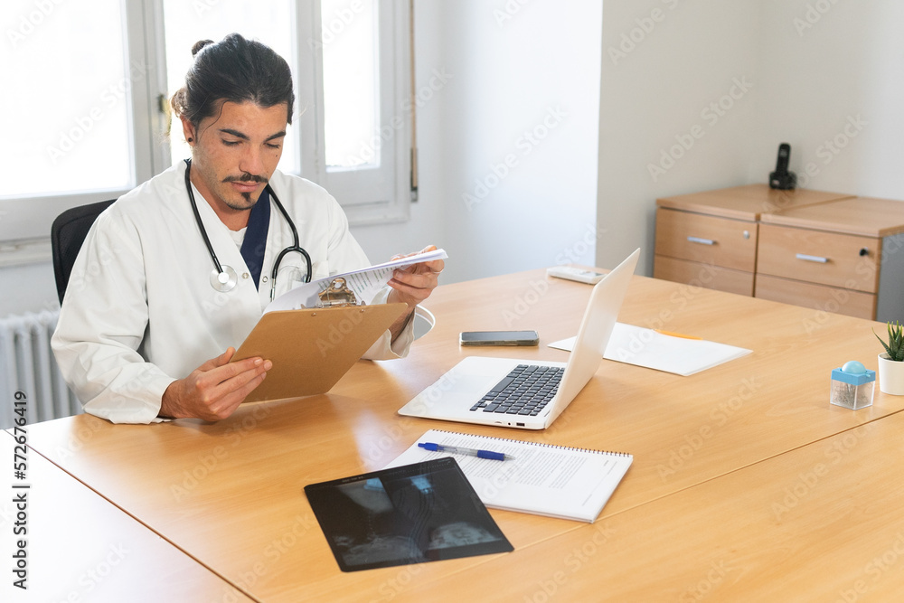 Focused doctor checking information on clipboard Focused doctor checking information on clipboard