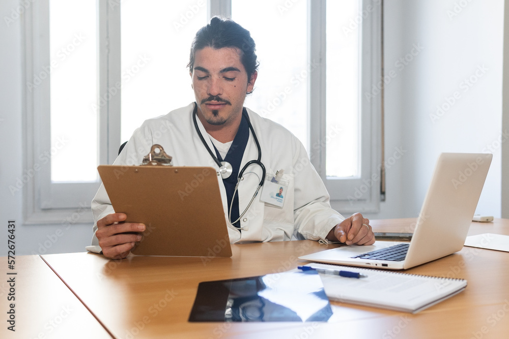 Focused doctor checking information on clipboard Focused doctor checking information on clipboard