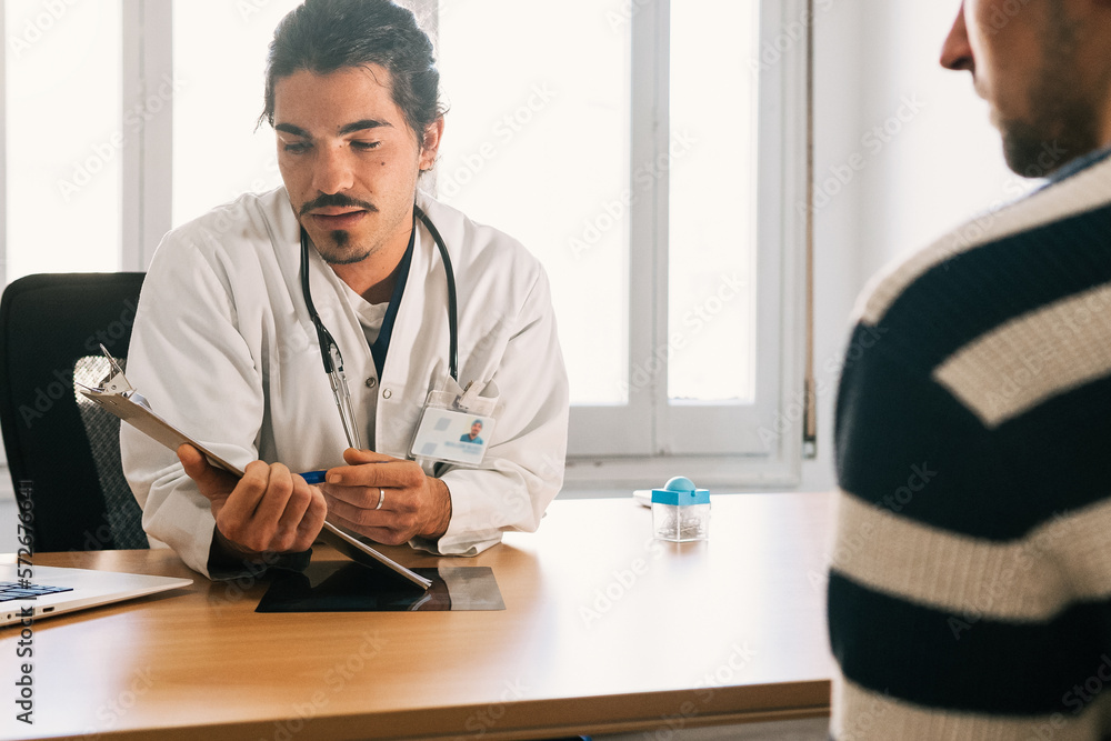 Cheerful ethnic doctor with clipboard and patient in hospital Cheerful ethnic doctor with clipboard and patient in hospital