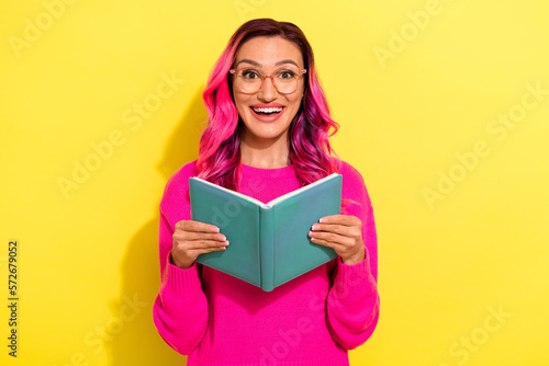 Photo of excited funky girl dressed vibrant pullover eyewear reading book isolated yellow color background